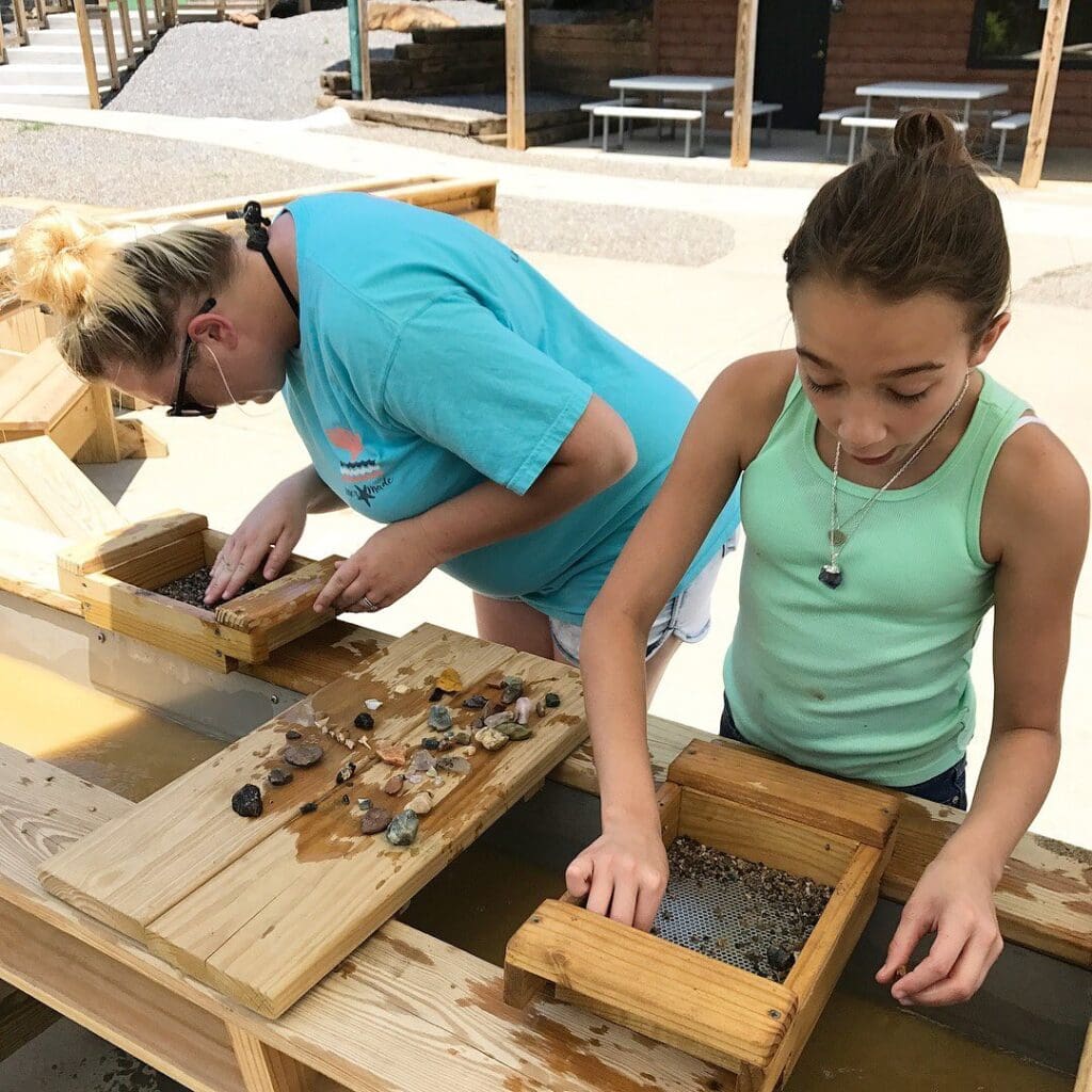 a woman and a girl mining gems at a wooden table